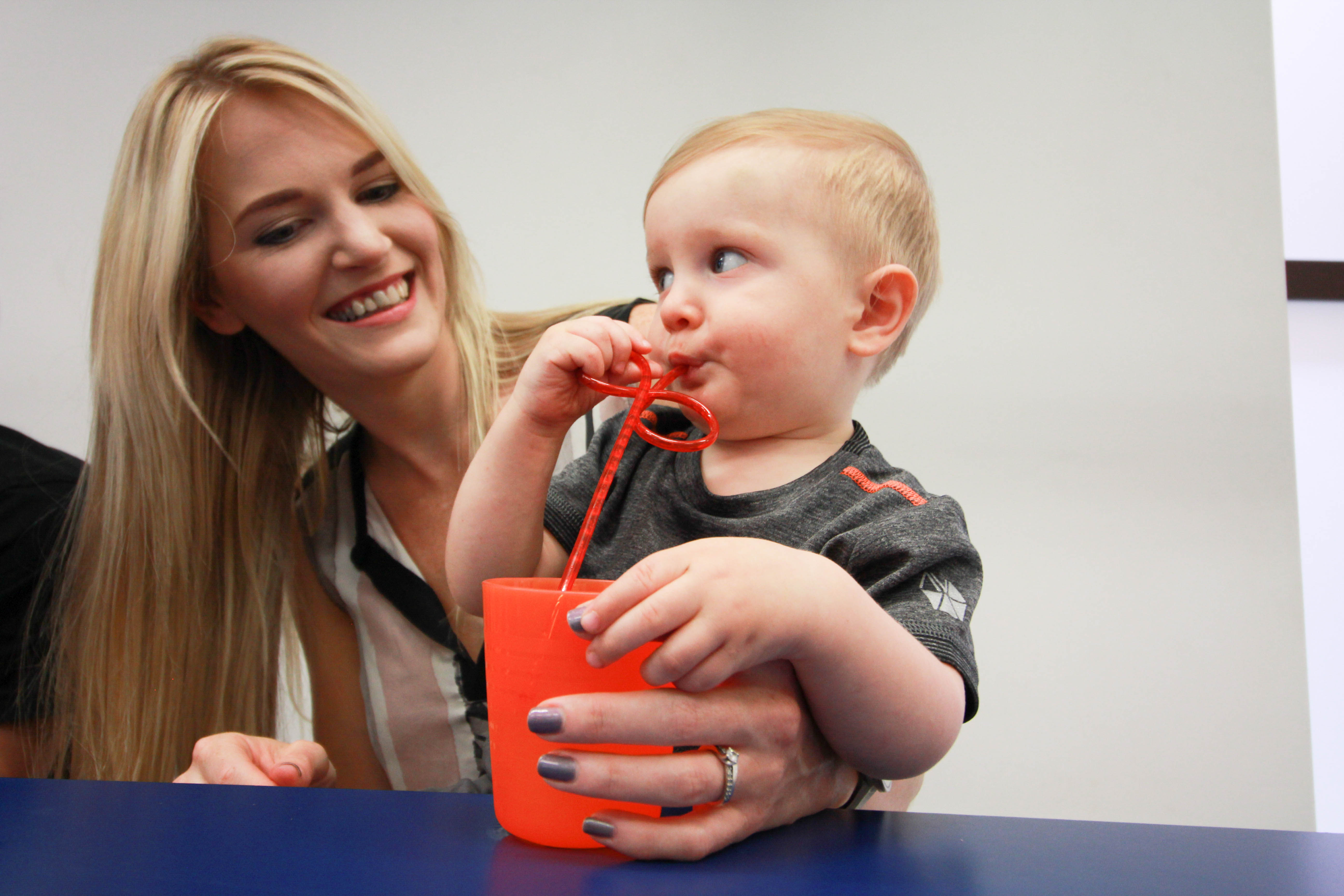 Kairon feeding himself with straw with mum