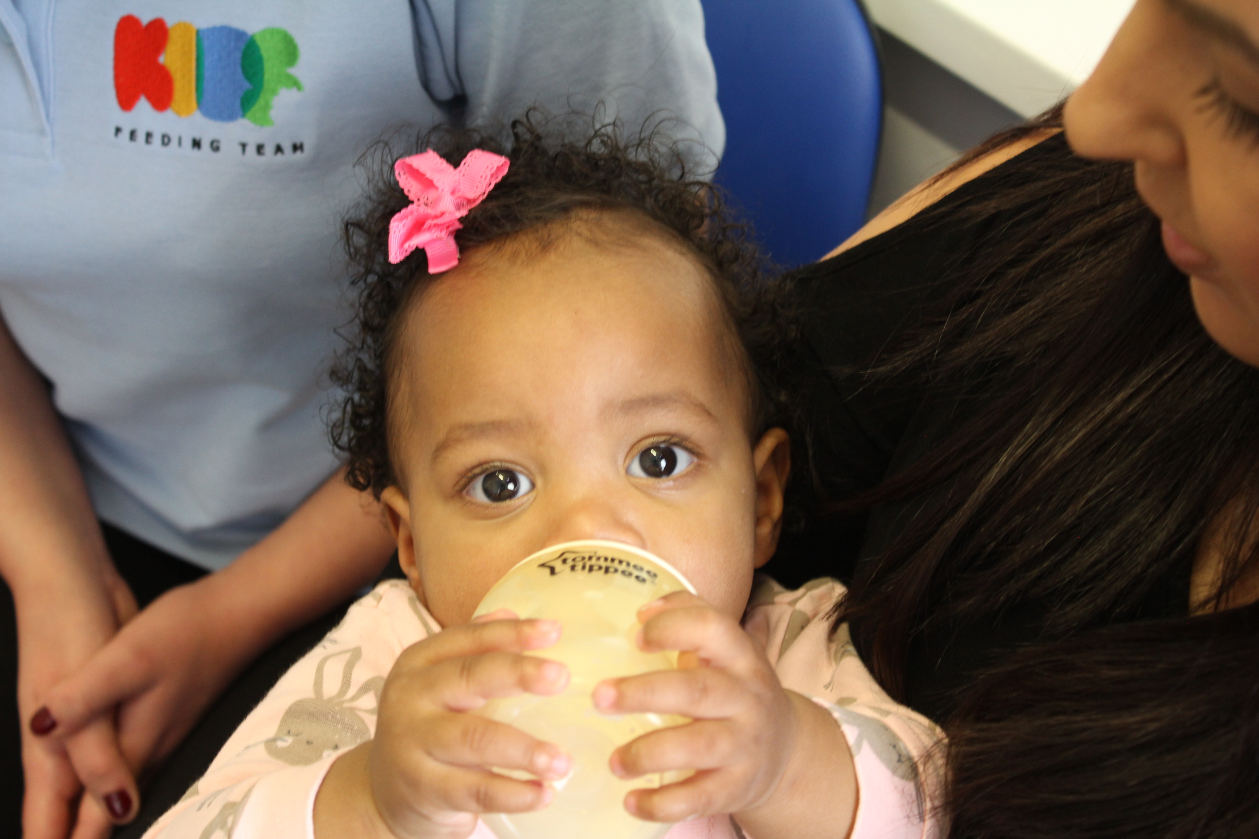 Jada feeding herself with bottle looking into camera