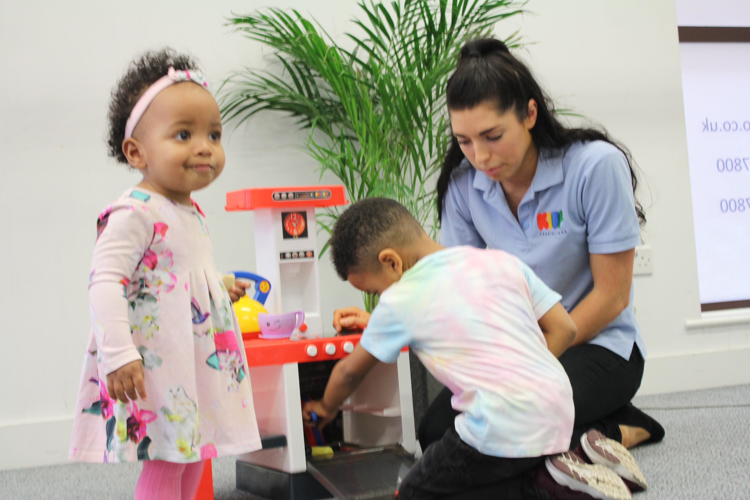 Ezra and Jada playing with toy kitchen